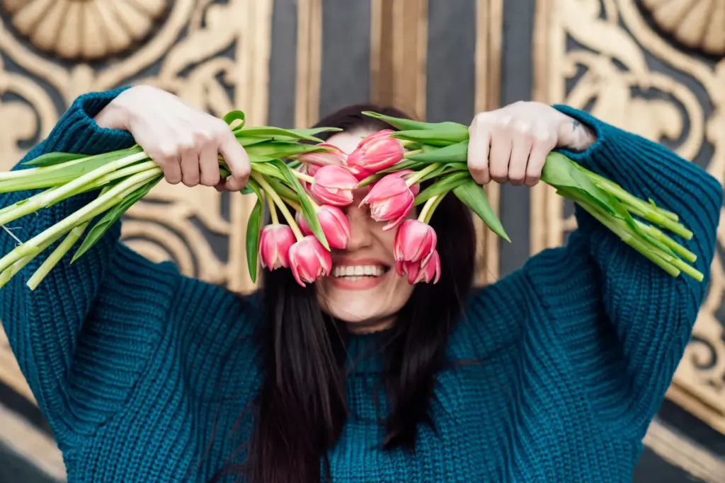 junge Frau hebt Blumen vor ihr Gesicht