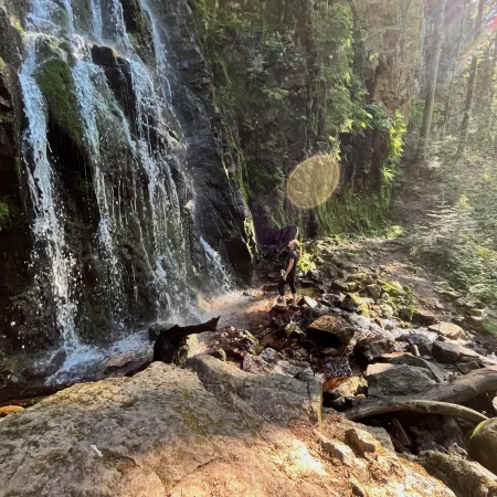 Frau steht vor einem Wasserfall